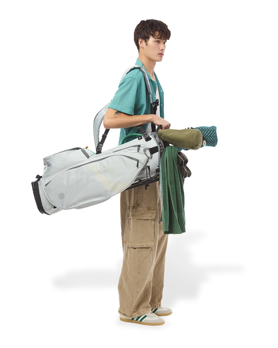 Golfer carrying the Verdant Mist Linkslite Explorer stand bag over one shoulder on the course.